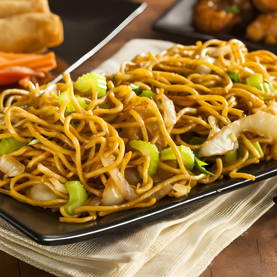Close-up of West Covina Thai Cuisine's golden noodles with green onions and white vegetables.